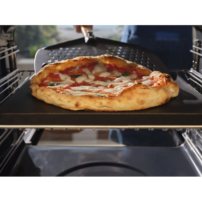A neapolitan pizza baking inside the pizza expert oven with a pizza peel underneath