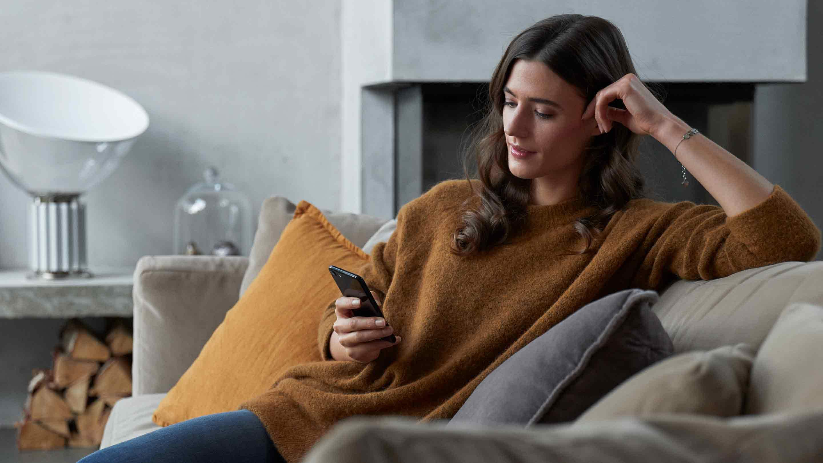 Donna seduta sul divano con telefono